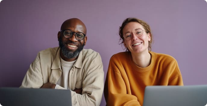 Two colleagues smiling at their laptops