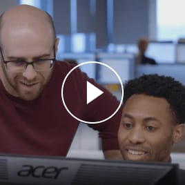 two male coworkers looking at a computer monitor together