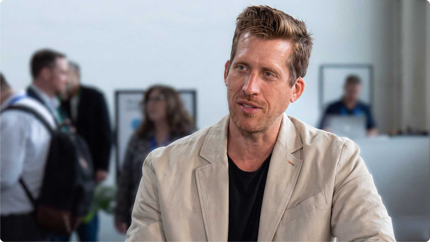 monday.com co-CEO Eran Zinman, in a beige blazer, speaking during a theCube interview at a conference